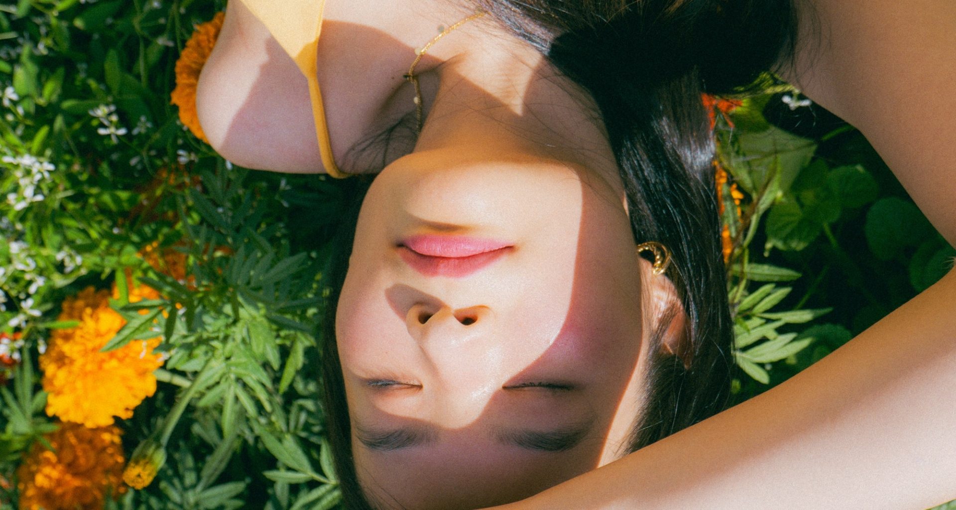 A person lies amongst a bed of marigolds.
